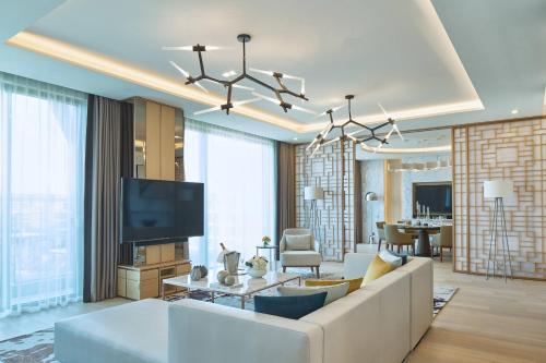 a living room with a white couch and a tv at Marriott Jeju Shinhwa World Hotel in Seogwipo
