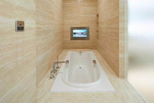 a bath tub in a bathroom with a tv at Marriott Jeju Shinhwa World Hotel in Seogwipo