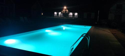 a swimming pool lit up at night with a light at Domki Mewa in Jantar
