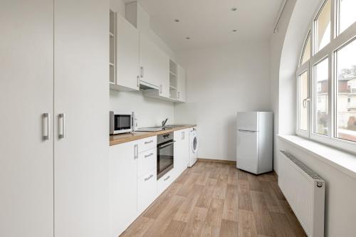 a kitchen with white cabinets and a white refrigerator at Villa Matylda in Mariánské Lázně