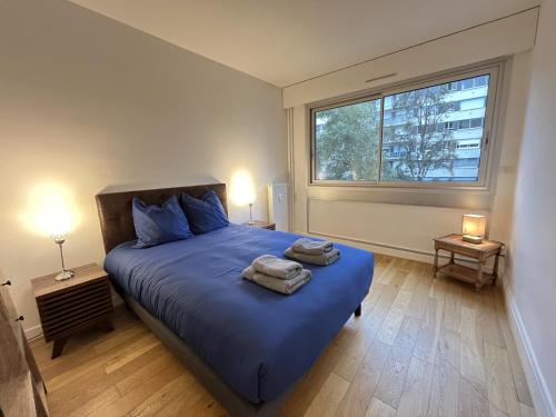 une chambre avec un lit bleu avec deux serviettes dessus dans l'établissement Le Chapitre - Le Mans Centre - Parking - Balcon, au Mans