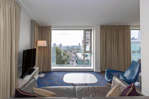 a living room with a couch and a large window at DoubleTree by Hilton Hotel London - Tower of London in London