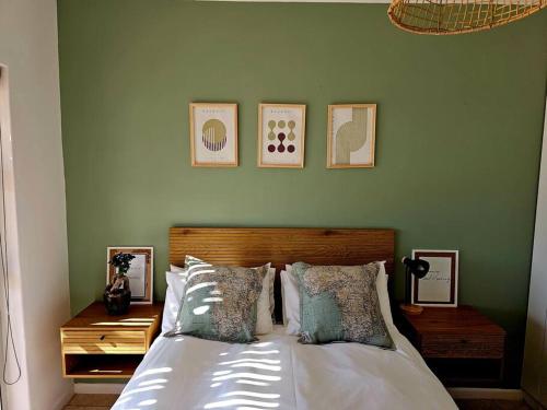 a bedroom with a bed with four pictures on the wall at Tus Nua in Langebaan