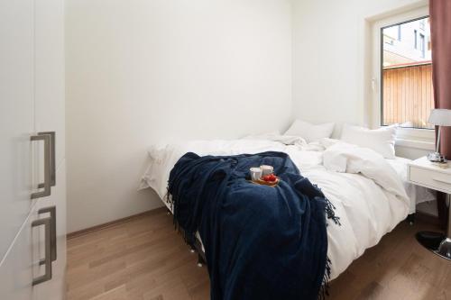 a white bed with a blue blanket and a cup on it at BJØRVIKA APARTMENTS, Opera Area, Oslo city center in Oslo