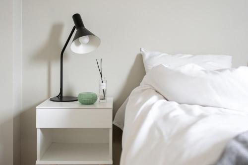 a bed with a lamp on a night stand next to a bed at BJØRVIKA APARTMENTS, Opera Area, Oslo city center in Oslo