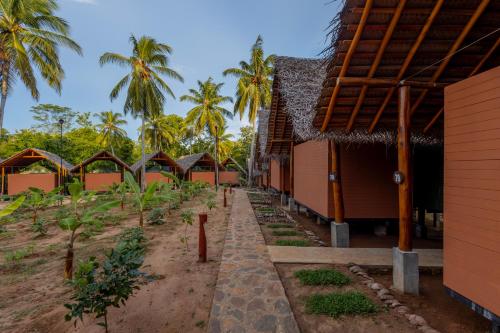 a row of houses with palm trees in the background at Athgira River Camping - Udawalawe in Udawalawe