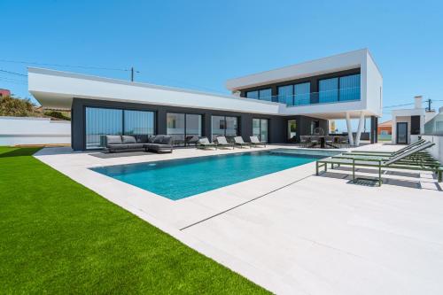 a villa with a swimming pool and a house at Casa Caracol, with a panoramic ocean view in Lourinhã