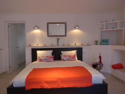 a bedroom with a large bed with an orange blanket at Villa Torre al Mar in Cala Santanyi