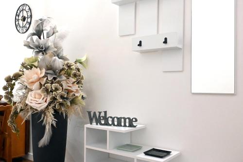 a vase with a welcome sign next to a wall at Il nido di Elisa in Albano Laziale