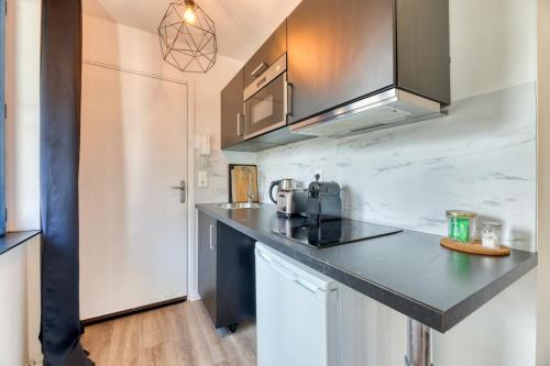 une cuisine avec un comptoir noir dans une pièce dans l'établissement Le Golden Black à Rouen !, à Rouen