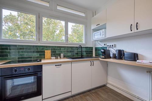 une cuisine avec des armoires blanches et des appareils noirs dans l'établissement La Suite des 3 Tours spacieux 3 chambres, à Rouen