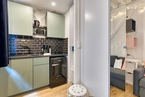 Elle comprend une petite cuisine avec des placards blancs et un mur en briques. dans l'établissement Alexandra joli studio centre, à Rouen