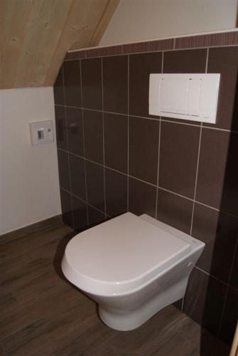 a white toilet in a bathroom with brown tiles at Gîte Binnert Bader in Nothalten