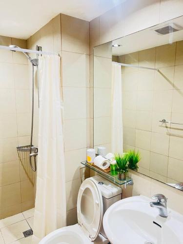 a bathroom with a toilet and a sink and a mirror at Alphas Haven in Manila