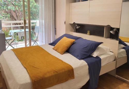 - une chambre avec un lit doté d'oreillers jaunes et bleus dans l'établissement Charmant 2 pièces, traversant, clim, wifi, parking, à Cannes