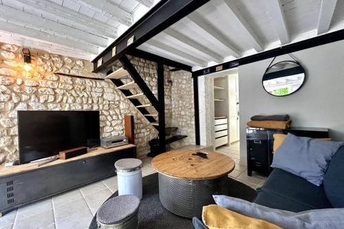 un salon avec une télévision, un canapé et une table dans l'établissement Le Saint-Ouen charmante maison tout confort !, à Les Authieux-sur-le-Port-Saint-Ouen