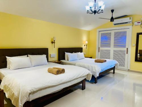 two beds in a room with yellow walls at Cocos Beach Resort in Palolem
