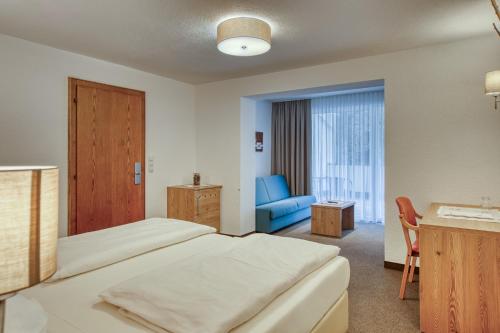a hotel room with a bed and a blue chair at Hotel Erika in Nauders