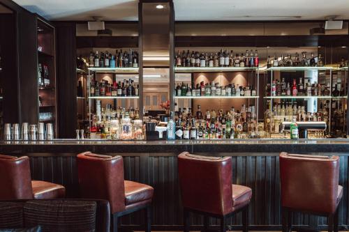 a bar with brown leather chairs in a room at Althoff Seehotel Überfahrt in Rottach-Egern