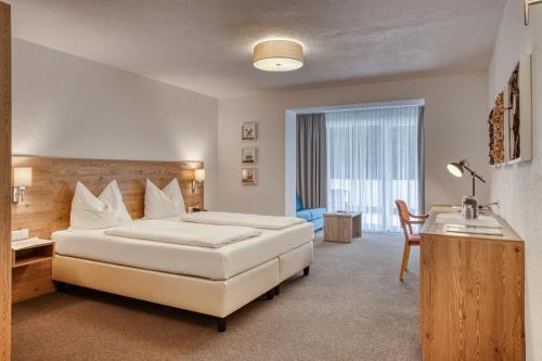 a hotel room with two beds and a table and a desk at Hotel Erika in Nauders