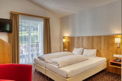a bedroom with a large bed and a large window at Hotel Erika in Nauders