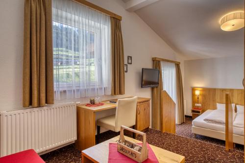a hotel room with a desk and a bed at Hotel Erika in Nauders