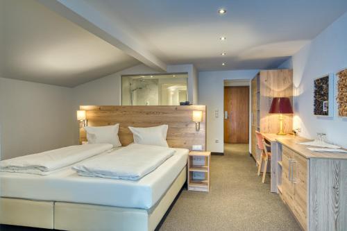 a bedroom with two beds and a desk at Hotel Erika in Nauders