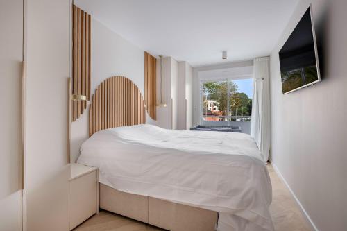 une chambre blanche avec un lit et une télévision dans l'établissement Appartement de standing en front de mer, pour 4, à La Baule