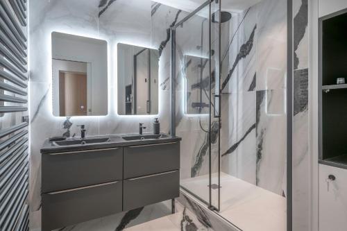 une salle de bain avec un lavabo et deux miroirs dans l'établissement Appartement de standing en front de mer, pour 4, à La Baule