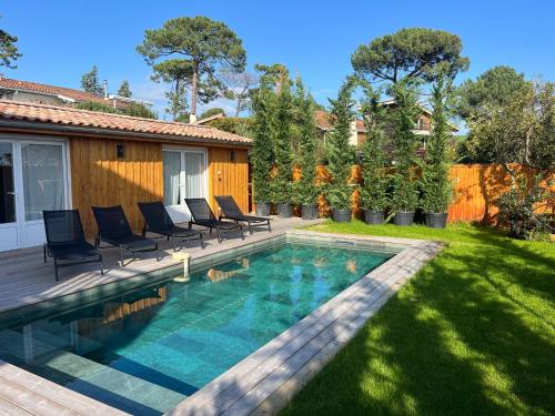 une cour avec une piscine entourée de chaises et une clôture dans l'établissement Villa Louis - Grand Piquey, à Lège-Cap-Ferret