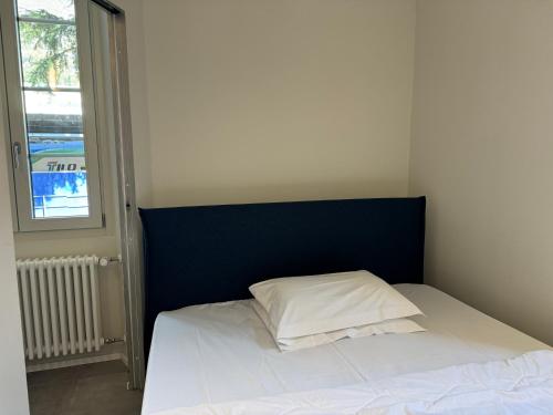 a bed with a blue headboard and a white pillow at Appartamento Food Truck 11 in Muralto