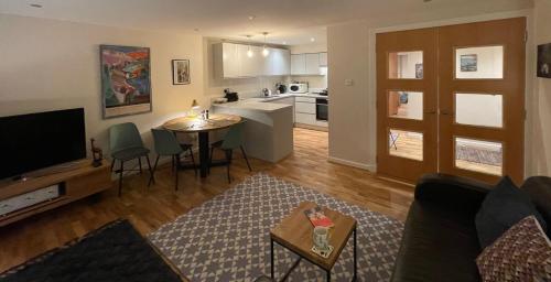 a living room with a couch and a table and a kitchen at The Art Flat Woodlands in Glasgow