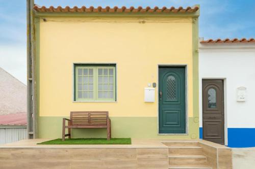 a house with a green door and a bench at A casa da Ermida de Aljustrel in Aljustrel