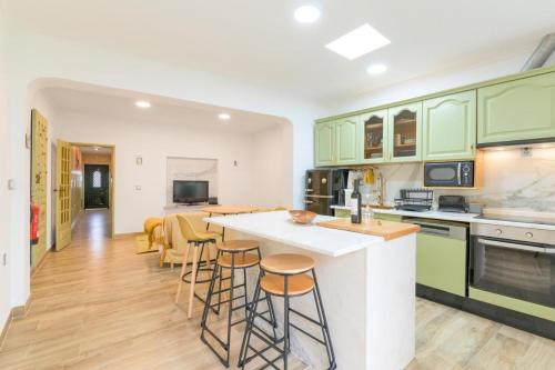 a kitchen with green cabinets and a counter with stools at A casa da Ermida de Aljustrel in Aljustrel