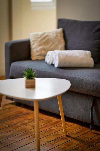 - une table basse blanche devant un canapé dans l'établissement L'Oiseau Blanc un petit nid proche de la gare !, à Rouen