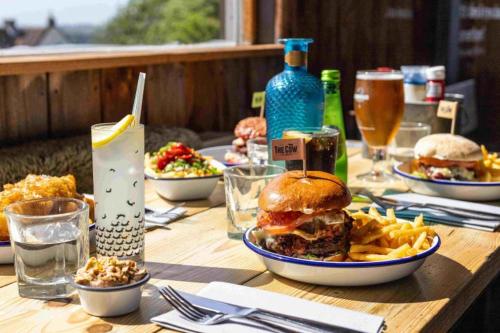 a wooden table with plates of food and a sandwich and fries at West Chalet At Tapnell Farm in Yarmouth