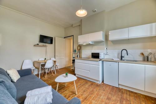 un salon avec un canapé bleu et une cuisine dans l'établissement L'Oiseau Blanc un petit nid proche de la gare !, à Rouen