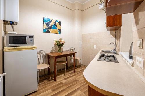 eine kleine Küche mit Tisch und Kühlschrank in der Unterkunft Apartment on Virmens`ka Street in Lwiw