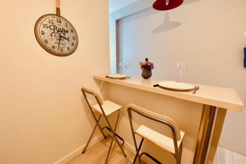 une salle à manger avec deux chaises et une table avec une horloge dans l'établissement Bright duplex 50m from the port of La Rochelle, à La Rochelle