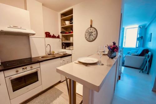 une cuisine avec des placards blancs et un comptoir avec une table dans l'établissement Bright duplex 50m from the port of La Rochelle, à La Rochelle