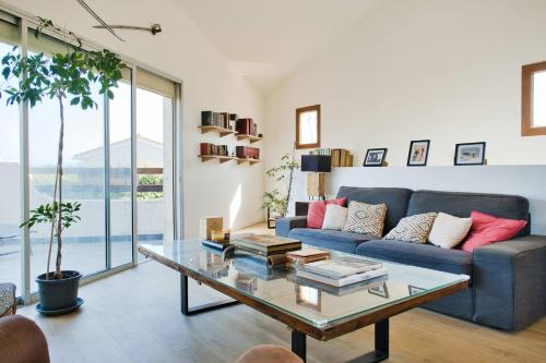 un salon avec un canapé bleu et une table en verre dans l'établissement Comfortable and spacious house with terraces, à Saint-Nazaire