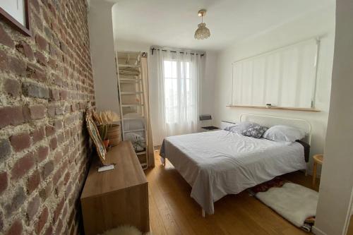 une chambre avec un lit et un mur de briques dans l'établissement Quiet bright apartment near Paris, à Clichy