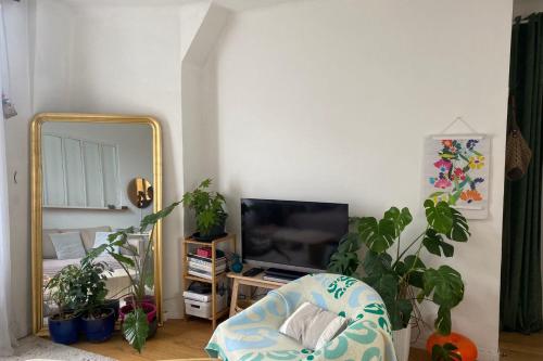 un salon avec un miroir et une chaise dans l'établissement Quiet bright apartment near Paris, à Clichy