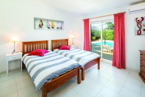 two beds in a bedroom with a view of a pool at Casa Santalena in Carvoeiro