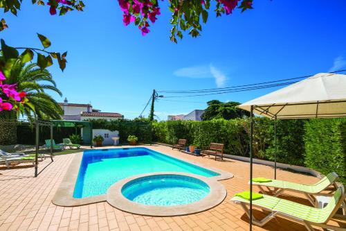 a swimming pool with two chairs and an umbrella at Casa Santalena in Carvoeiro