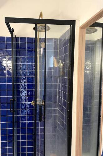 La salle de bains est pourvue d'une douche en verre avec du carrelage bleu. dans l'établissement Appartement entre Endoume et Samatan, à Marseille