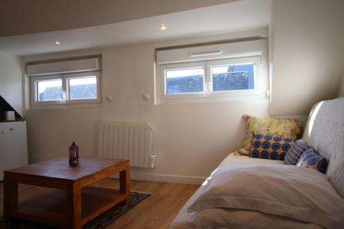 une chambre avec un lit, une table et des fenêtres dans l'établissement Le Petit Nid en plein centre-ville de Rouen !, à Rouen