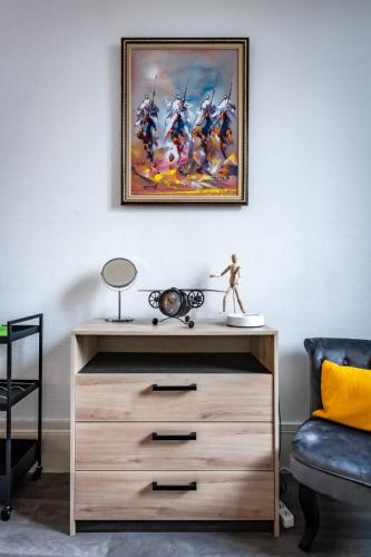 - une commode dans un salon orné d'une peinture murale dans l'établissement Gary joli F2 au pied de la Gare de Rouen, à Rouen