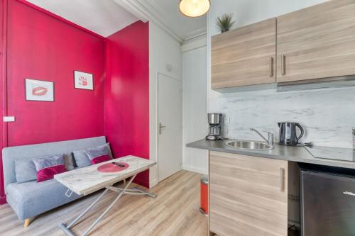 une cuisine avec un canapé et un mur rouge dans l'établissement Le Red Touch votre F2 au cœur de Rouen !, à Rouen