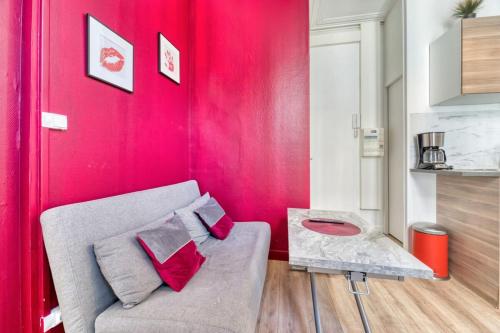 - un salon avec un canapé et un mur rouge dans l'établissement Le Red Touch votre F2 au cœur de Rouen !, à Rouen